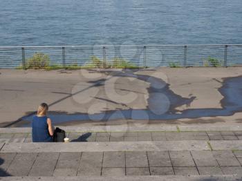 unrecognisable woman looking at river Rhine in Duesseldorf, Germany