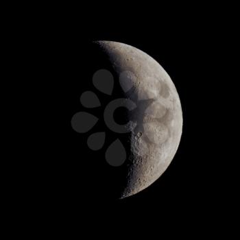 First quarter moon over dark black sky seen with a telescope from northern emisphere at night