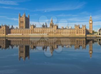 Houses of Parliament (aka Westminster Palace) reflected in river Thames water in London, UK