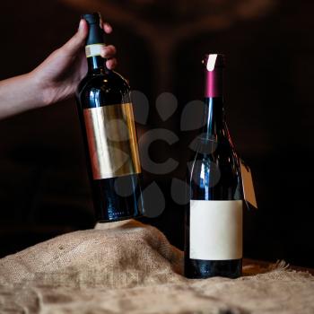 Woman taking new wine bottle on a dark background