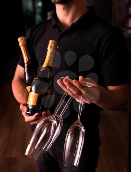 Man holding Champagne and glasses on dark background