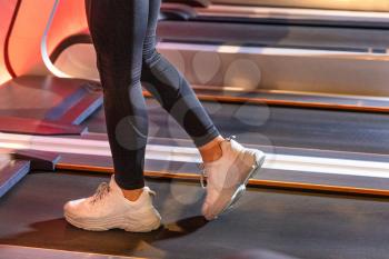Fitness girl running on treadmill with white shoes
