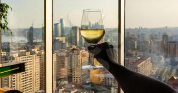 Woman holding white wine glass with city view