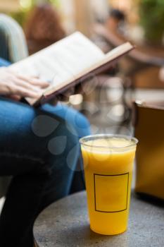 Woman reading the book with orange cocktail at cafe