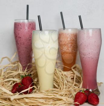 Fruit milky cocktails with strawberry on a straw