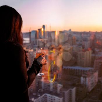 Woman holding champagne glass, looks at the city view