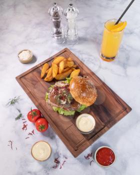 Tasty burger with fried potato, juice on wooden plate