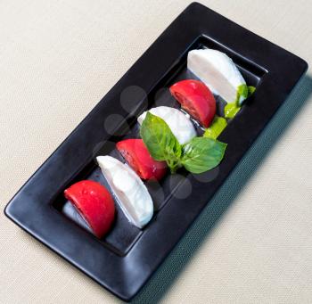 Beautiful ice cream balls with tomato on the black plate