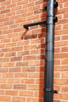 Royalty Free Photo of a Black Tube on a Brick House