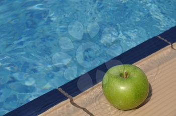 Royalty Free Photo of an Apple by a Poolside 