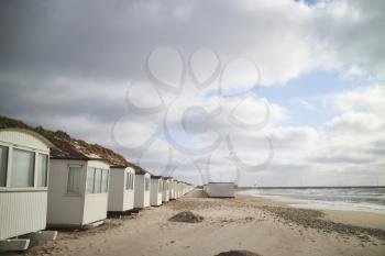A row of beach cabins with clouds