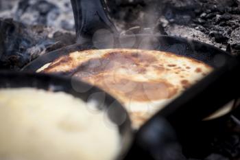 Cooking pancakes over open fire outdoors