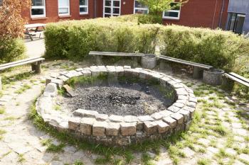A handmade fireplace outdoors with seating at a school