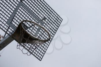 Closeup of a metal and rustic basketball hoop on a cloudy day