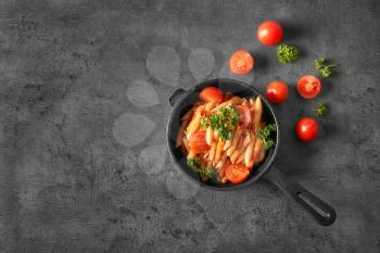 Pan with tasty pasta in tomato sauce on grey background, top view�