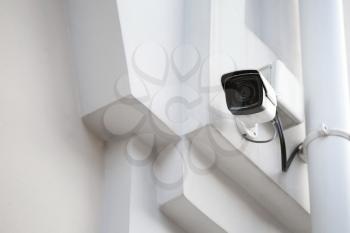Modern CCTV camera on wall of building outdoors�