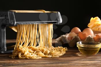 Metal pasta maker with dough and products on kitchen table�