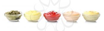 Different tasty sauces in glass bowls on white background�