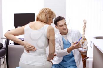 Orthopedist showing spine model to patient in hospital�