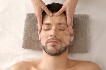 Handsome man having head massage in spa salon�