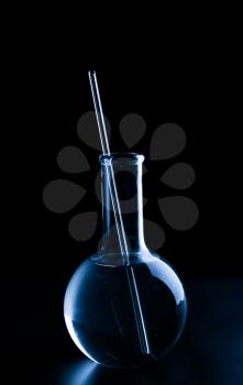 Volumetric flask with liquid and pipette on black background�