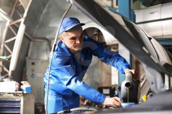 Male mechanic refilling car oil in service center�