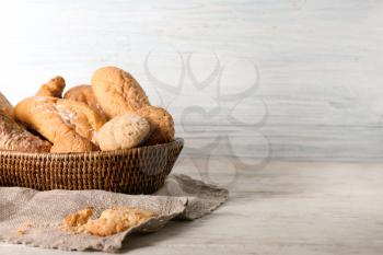 Wicker basket with fresh tasty bakery products on table�