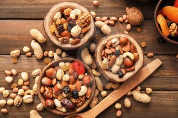 Bowls with various tasty nuts on wooden table 