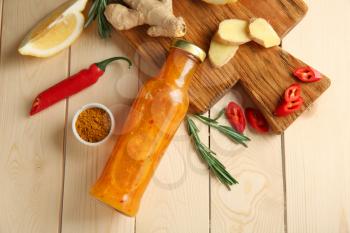 Composition with bottle of tasty sauce and vegetables on wooden background�