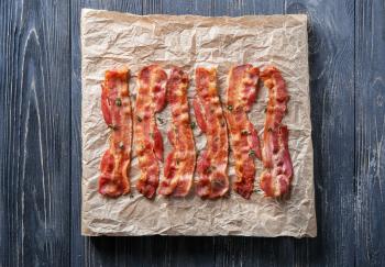 Parchment with tasty fried bacon on wooden table�
