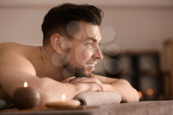 Young man relaxing on massage table in spa salon�