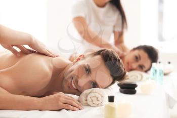 Happy young couple having massage in spa salon�