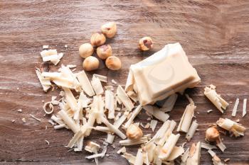 White chocolate curls with hazelnuts on wooden table�
