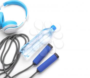 Jump rope, bottle of water and headphones on white background�