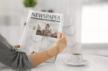 Woman holding morning newspaper at home�