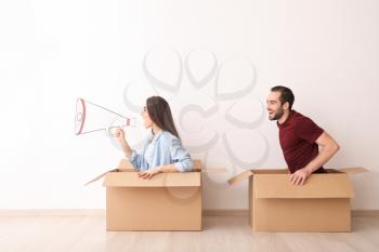 Young couple playing with boxes indoors. Moving into new house�
