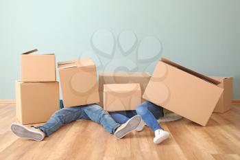 Young couple buried under heap of boxes indoors. Moving into new house�
