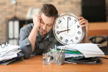 Tired businessman with clock in office. Time management concept�