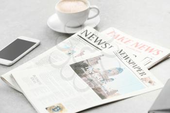 Morning newspapers, cup of hot coffee and phone on grey table�