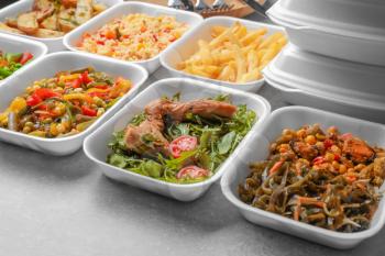 Foam plastic containers with delicious food on table�