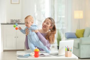 Young mother with baby working at home�