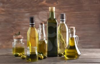 Glassware with olive oil on wooden background�