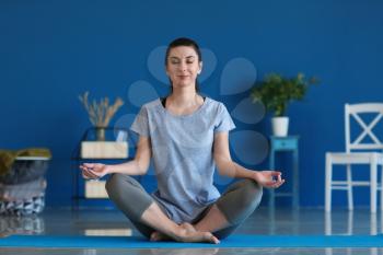 Young woman practicing yoga indoors�