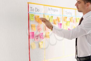 Man near scrum task board with stickers in office�