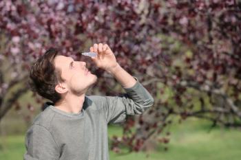 Young man using eye drops near blooming tree. Allergy concept�