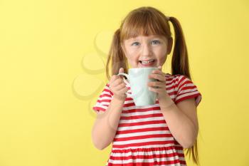 Cute little girl with cup of hot cocoa drink on color background�