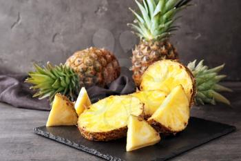 Slate plate with delicious cut pineapples on table�
