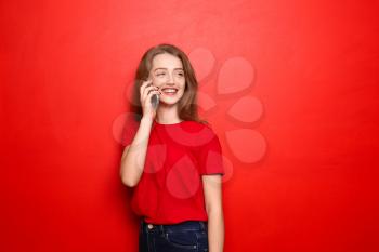 Beautiful young woman talking on mobile phone against color background�