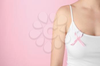 Woman with pink ribbon against color background. Breast cancer awareness concept�