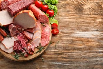Wooden board with assortment of delicious deli meats on wooden board�